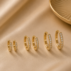 O Trio de brincos de argolinhas cravejadas folheado em ouro 18k é um conjunto elegante e versátil, perfeito para quem ama acessórios delicados e modernos. Com três tamanhos diferentes, as argolinhas permitem criar um mix de brincos harmonioso, valorizando a orelha com brilho e sofisticação.