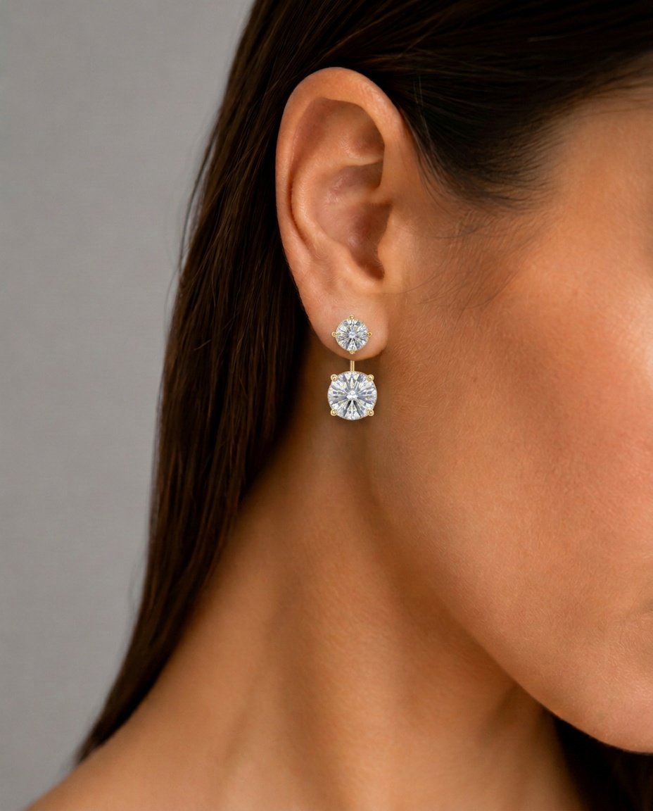 O Design Ear Jacket e a Modernidade do Brilho em Camadas Para as mulheres contemporâneas que buscam um acessório inovador, refinado e com forte impacto visual, o nosso Brinco Ear Jacket Zircônia Cristal com Banho em Outo 18k é a escolha perfeita. Conhecido por sua estrutura versátil, este modelo destaca um clássico ponto de luz redondo no lóbulo, de onde se conecta o pêndulo por trás da orelha sustentando uma zircônia central maior e imponente. O banho em Ouro 18k confere um acabamento de alto polimento espelhado, fazendo com que as pedras transparentes pulsem com a máxima luminosidade.